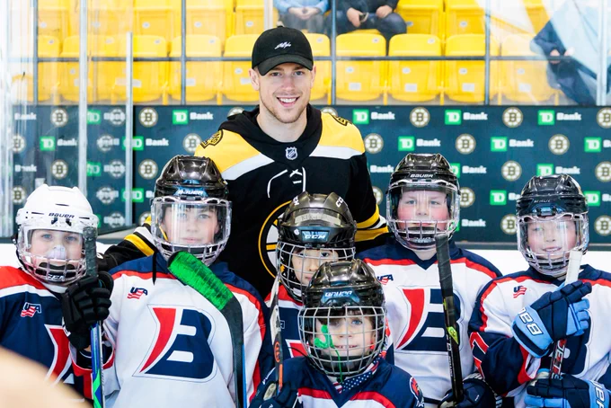 Charlie Coyle smiles as he poses for a photo with Brookline youth hockey players.