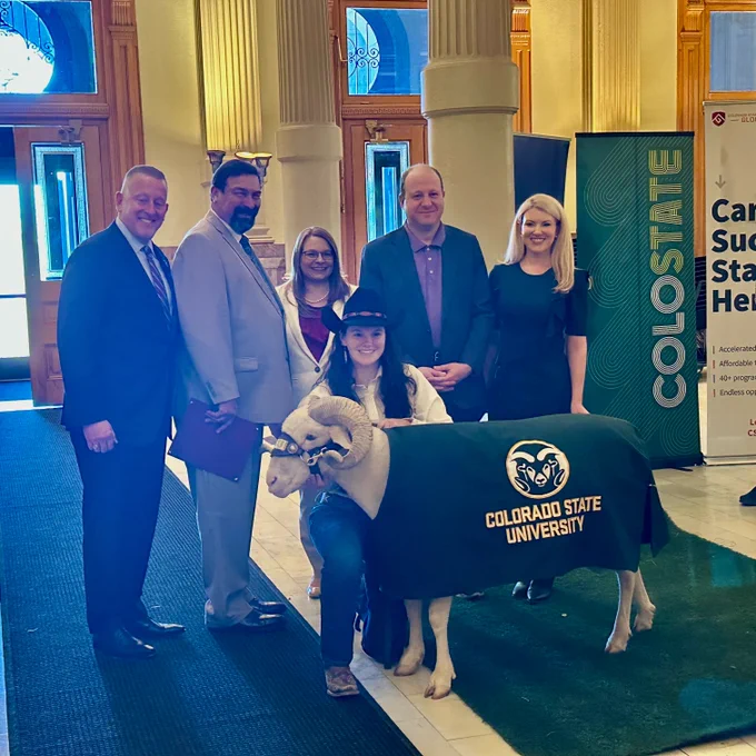 Tim Mottet, Tony Frank, Pamela Toney, Jared Polis, Amy Parsons, student Ram Handler and CAM the Ram pose for a photo in the Colorado State Capitol. 