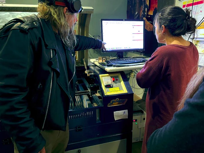 A hacker teaching another how to operate the laser cutter at Tampere Hacklab.