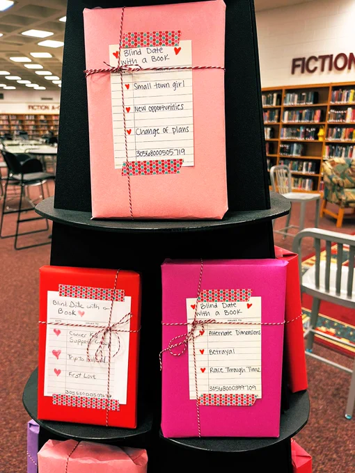 Books on a display pyramid wrapped in colorful paper with brief descriptions for a blind date