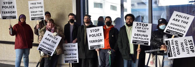 Community members stand inside the office, holding signs.