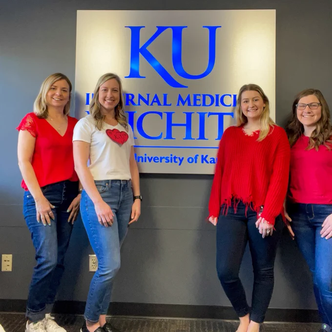 Staff wearing red stand in front of the KU School of Medicine-Wichita Internal Medicine sign