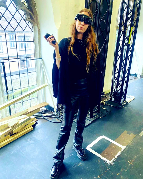 A woman stands in black clothing wearing a Magic Leap headset.