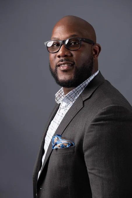 The image shows a headshot of Daemen double Alum, David Johnson, who recently won a Buffalo Business First IDEA award.  The image of Johnson is on a dark grey background. 