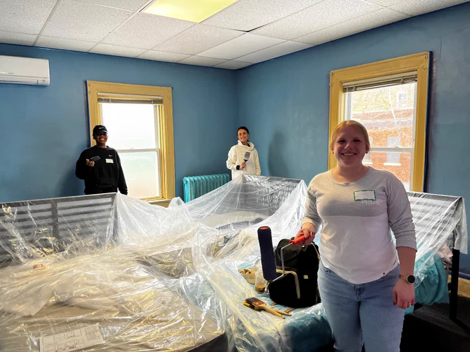 members painting a small room a deep blue color.