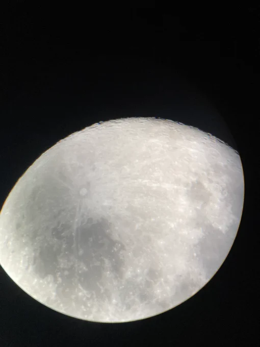 The Moon, partially obscured within the eyepiece of a telescope