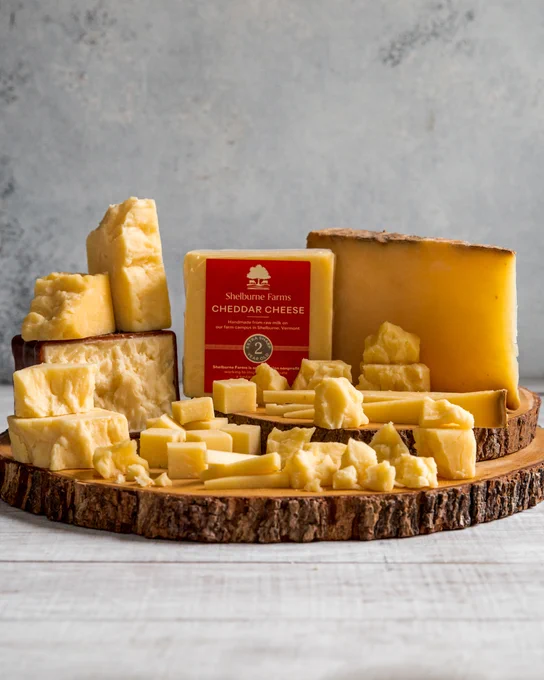 An assortment of Shelburne Farms cheeses, styled artfully on a cheese board.