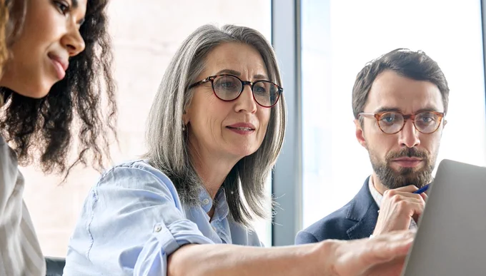 Group of three age diverse people looking at a computer screen