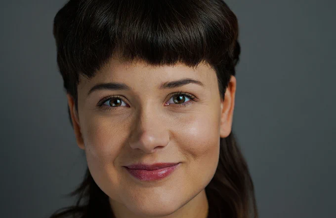 Isabella Sperotto smiling at the camera in front of a grey background. She has short brown hair with a fringe