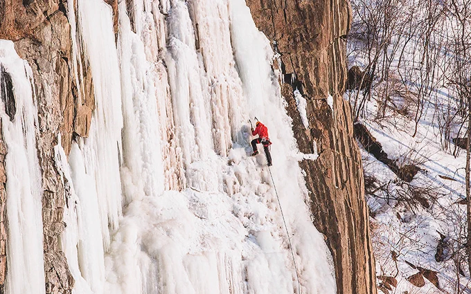 An ice climber on a ice covered rock face.