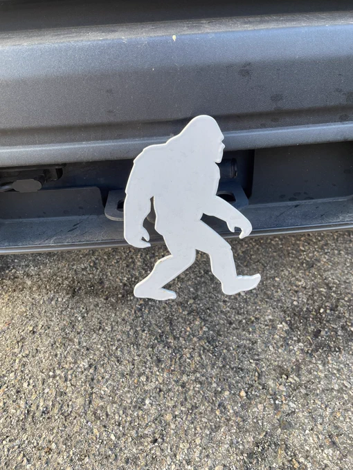 A dusty black bumper with a white silhouette of a Sasquatch attached to it.