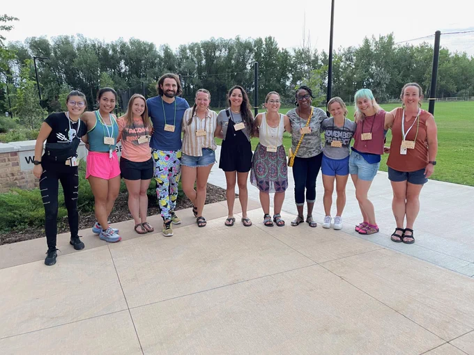Co-leaders of 2022 pledge class are commemorating their squad by taking a group photo in which they are standing shoulder-to-shoulder and smiling.