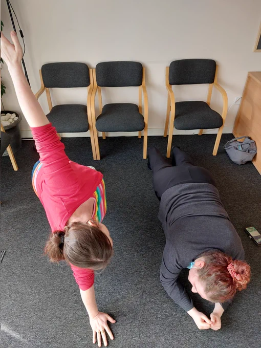 Isabelle and Georgina planking in the reception.  Isabelle is on her elbows, Georgina is doing a side plank 