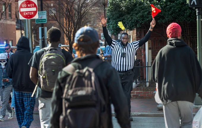 A VCU officer dressed as a referee throws a flag to encourage safe crosswalk activity.