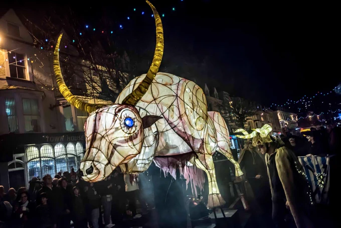 The Mythical Ox light-up sculpture paraded through a town, surrounded by people for Winter Light.
