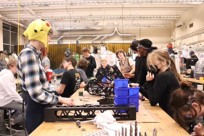 Many students working on assembling robot parts.