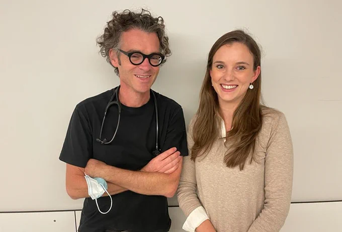 Dr. Wilfried Mullens & Dr. Evelyn Meekers poseren tegen een neutrale achtergrond. Dr. Mullens draagt een zwart t-shirt, heeft donkergrijs haar en draagt een bril. Dr. Meekers draagt een beige trui en heeft lang bruin haar. 