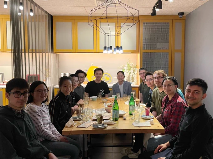 Twelve people sitting around a table at an Asian restaurant of some sort. It looks to be after the meal, because empty glasses are on the table and what looks to be some unfinished desserts. Prof. Crystal Chu is sitting at the head of the table, and is the only one not in casual clothes