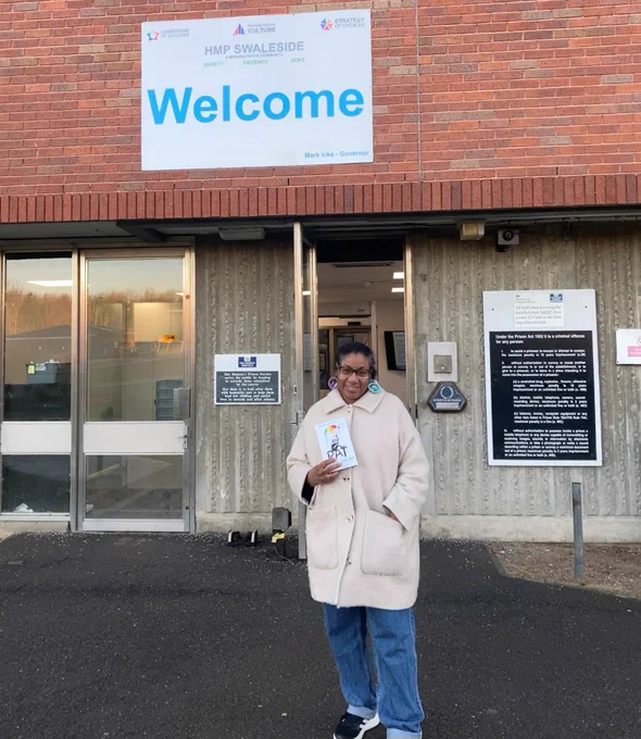 Patrice Lawrence holding the book "Rat" outside MHP Swaleside