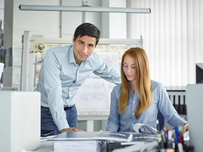 TAKRAF Group, through its established and well-known brands, TAKRAF and DELKOR, provides innovative technological solutions to the mining and associated industries. With ~1,000 employees across Europe, Africa, Asia, the Americas and Australia, we offer exciting and challenging global career opportunities. The picture shows an office workplace for commercial staff as well as two employees at their desk.