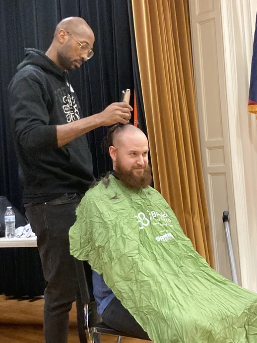 Barber shaves a person's head to support St. Baldrick's