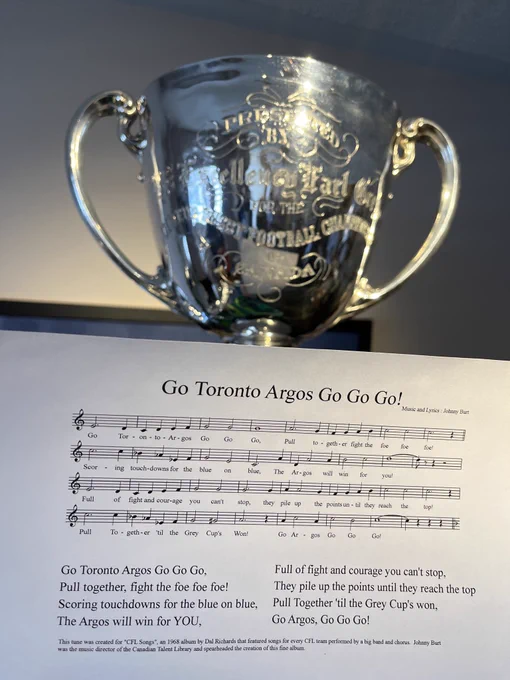 The Grey Cup, with the music and lyrics to "Go Argos Go" in front of it