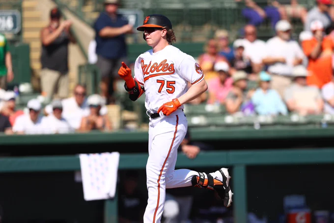 Heston running and pointing forward in an Orioles jersey and helmet