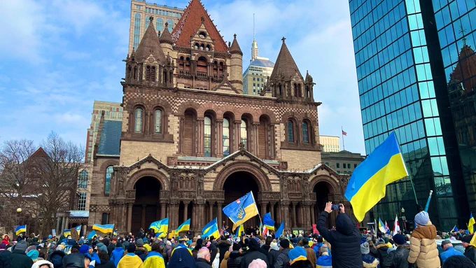 A crowd waves Ukrainian flags outside Trinity Church in Copley Square.