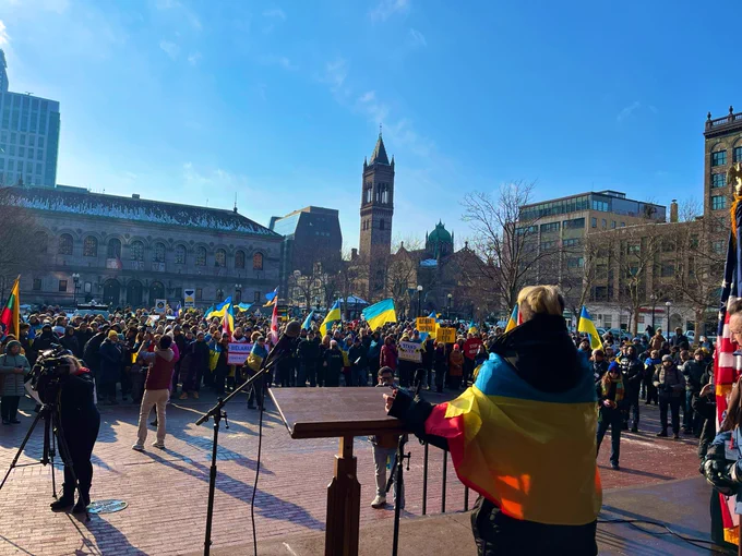 An MIT Ukrainian student wrapped in a Ukrainian flag & an LGBTQ  pride flag speaks about Ukraine and the defense of freedom of all kinds to the crowd that fills Copley Square.