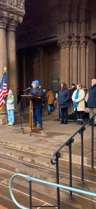 Councilor Bok speaks from the podium on the steps of Trinity Church; At-Large Councilors Louijeune, Murphy, and Flaherty stand behind.