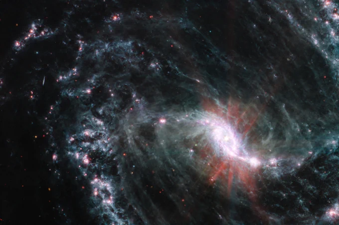 A large spiral galaxy takes up the entirety of the image, with the lower right portion of the galaxy’s spiral arms extending out of frame. The core of the galaxy i