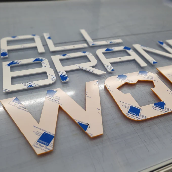 CNC perspex lettering set out on a workbench.