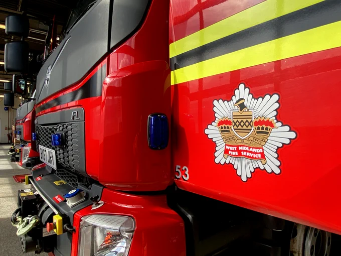 Front of a fire engine with it's door open showing West Midlands Fire Service crest.
