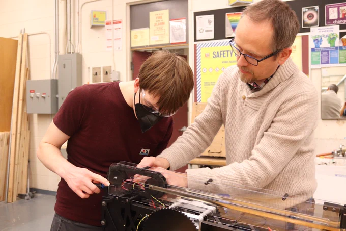 Mentor and student fixing a robot arm.