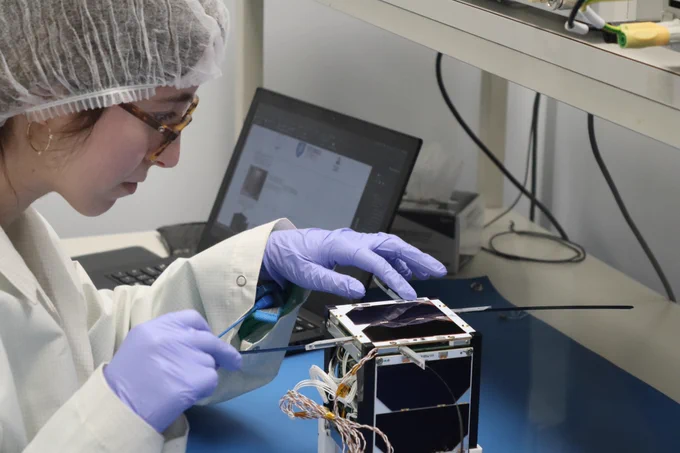 A researcher testing the nanosat in a clean room
