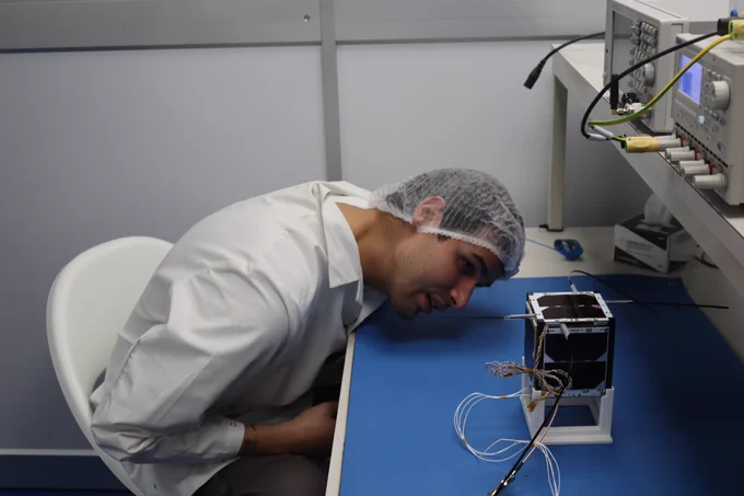 A researcher testing the nanosat in a clean room