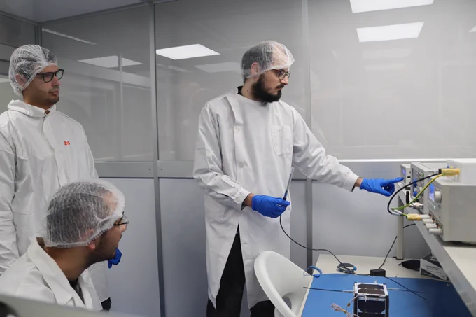 Three researchesr testing the nanosat in a clean room