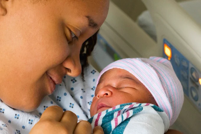Mother cradling newborn in the hospital.