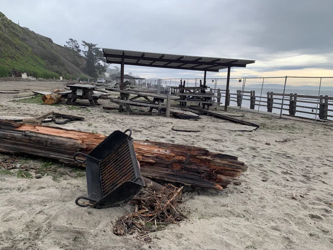 a driftwood log, overturned grill, and broken picnic tables at Seacliff state beach