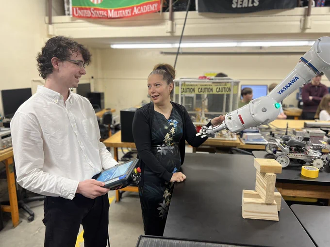 Student Logan shows Commissioner Infante-Green an industrial robotics arm.