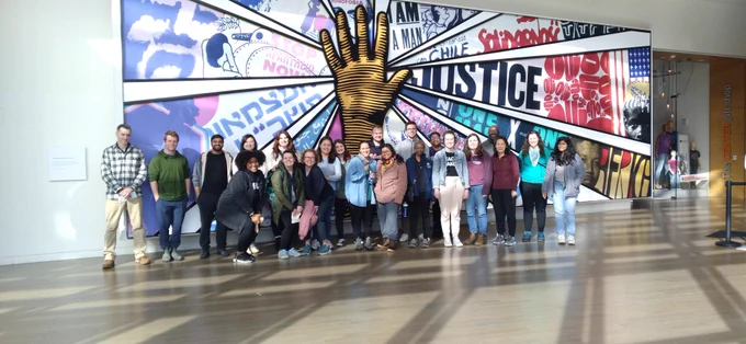 A group of students stands in front of a mural at the National Center for Civil and Human Rights.