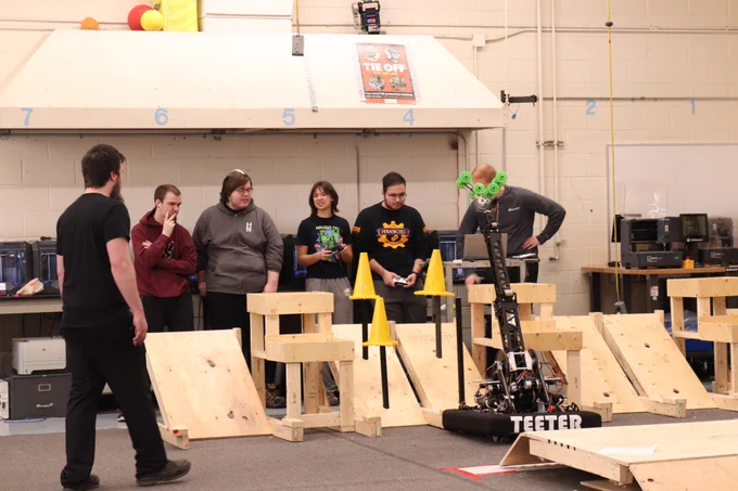 Many people looking the robot with its arm extended.