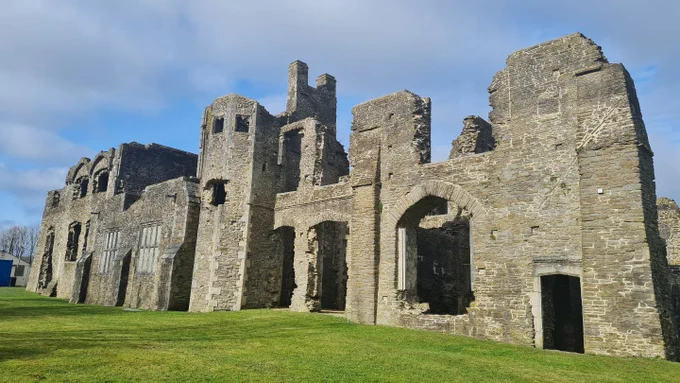Cefn y plasty Tuduraid gyda awyr las a chymylog. 