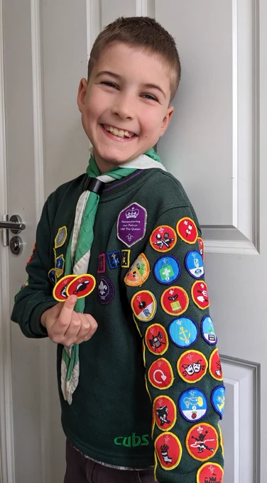 A Cub Scout with an arm full of badges holding two more