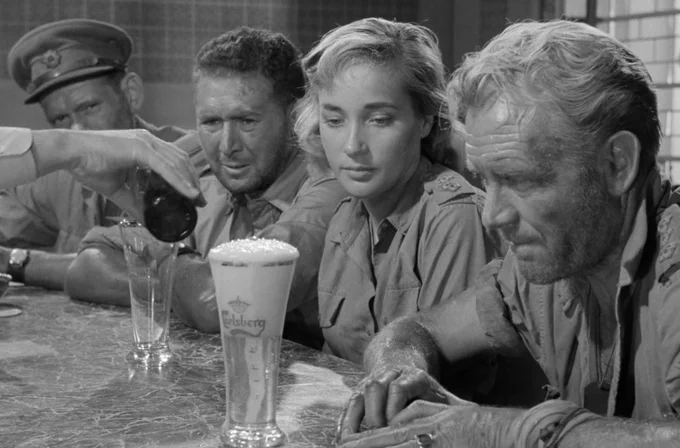 From "Ice cold in Alice": Four very dusty, sweaty, thirsty people look at a cold beer, freshly poured. It is the first they have seen in many weeks.