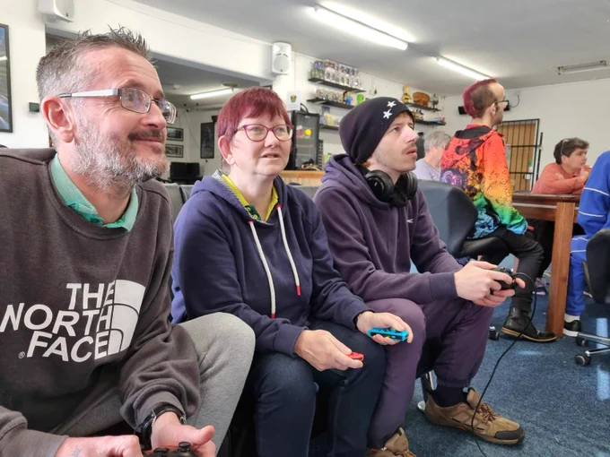 Three people playing on gaming consoles together.