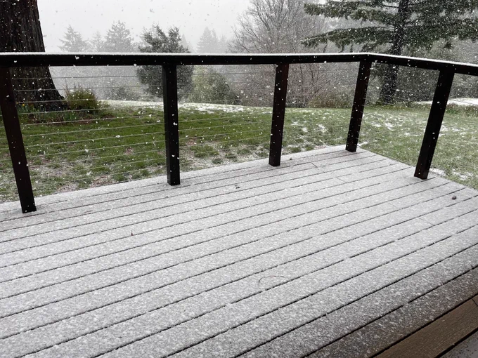 A light layer of snow on the deck with snow falling heavily all around 