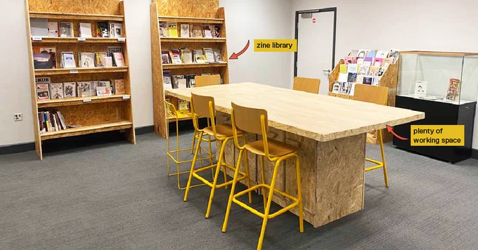Image of the zine maker space. Complete with a zine library, instructions on how to make a zine, a zine donation box, a zine vending machine and a printer