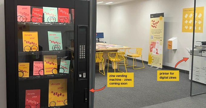 Image of the zine maker space. Complete with a zine library, instructions on how to make a zine, a zine donation box, a zine vending machine and a printer