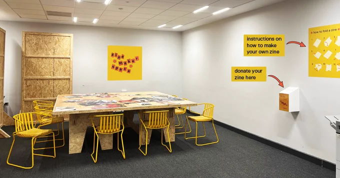 Image of the zine maker space. Complete with a zine library, instructions on how to make a zine, a zine donation box, a zine vending machine and a printer